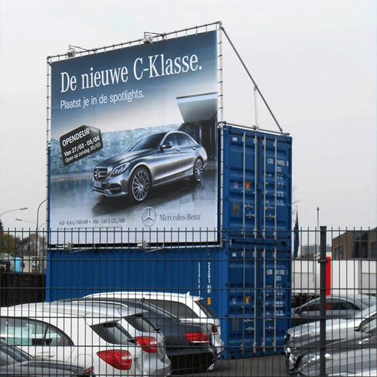 Groot spandoek Mercedes vastgemaakt aan containers