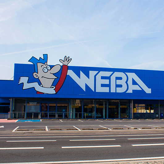 Creatieve plaatsing van het Weba logo en merknaam aan de bovenkant van het gebouw
